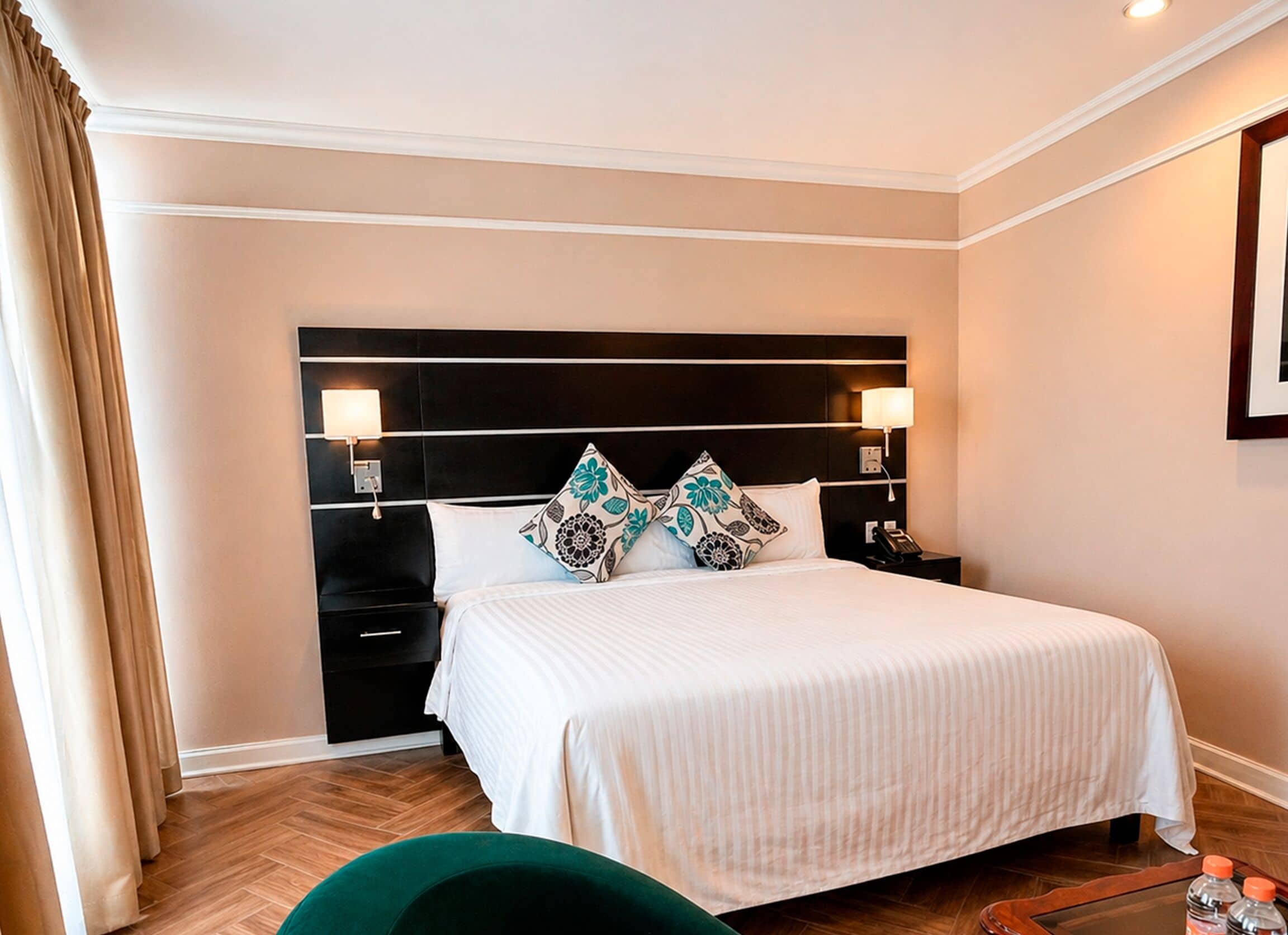 Ein Hotelzimmer mit einem großen Bett, Nachttischlampen, einem Nachttisch und einem grünen Sessel.