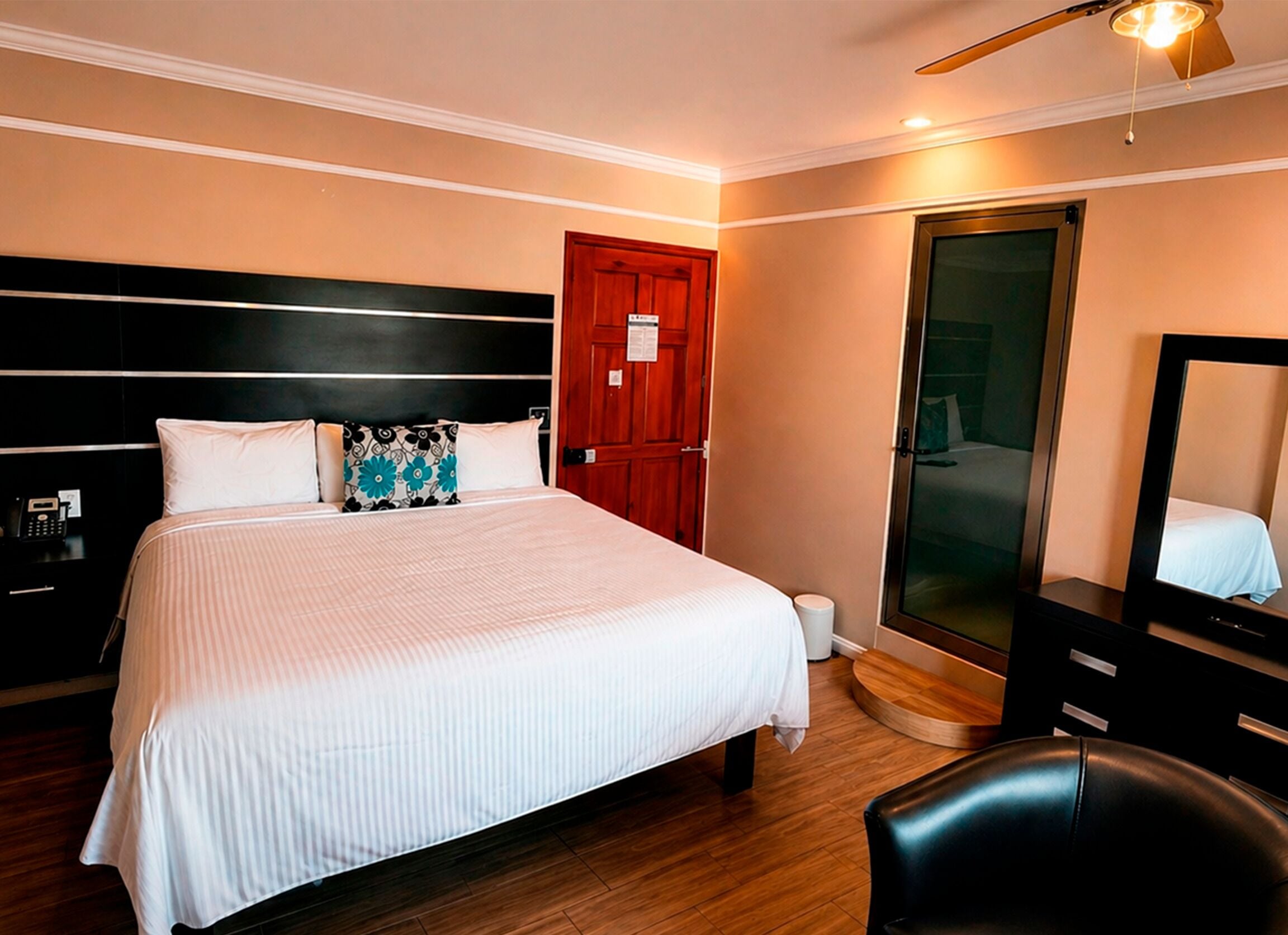 Una habitación de hotel con una cama grande, cabecera de madera, un espejo, un escritorio y un armario.