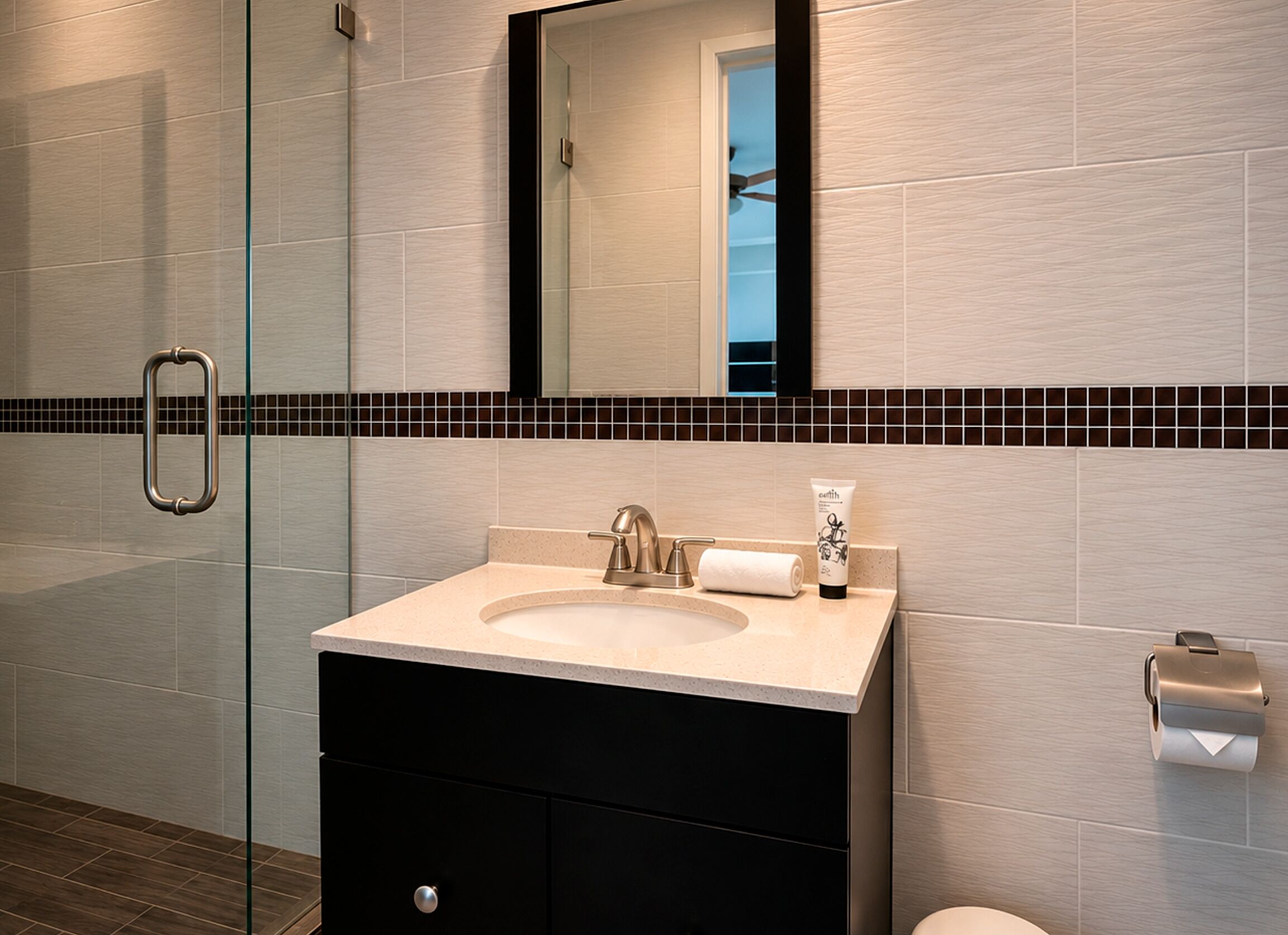 A modern bathroom with a glass shower enclosure, a sink with a towel, and a toilet paper holder.