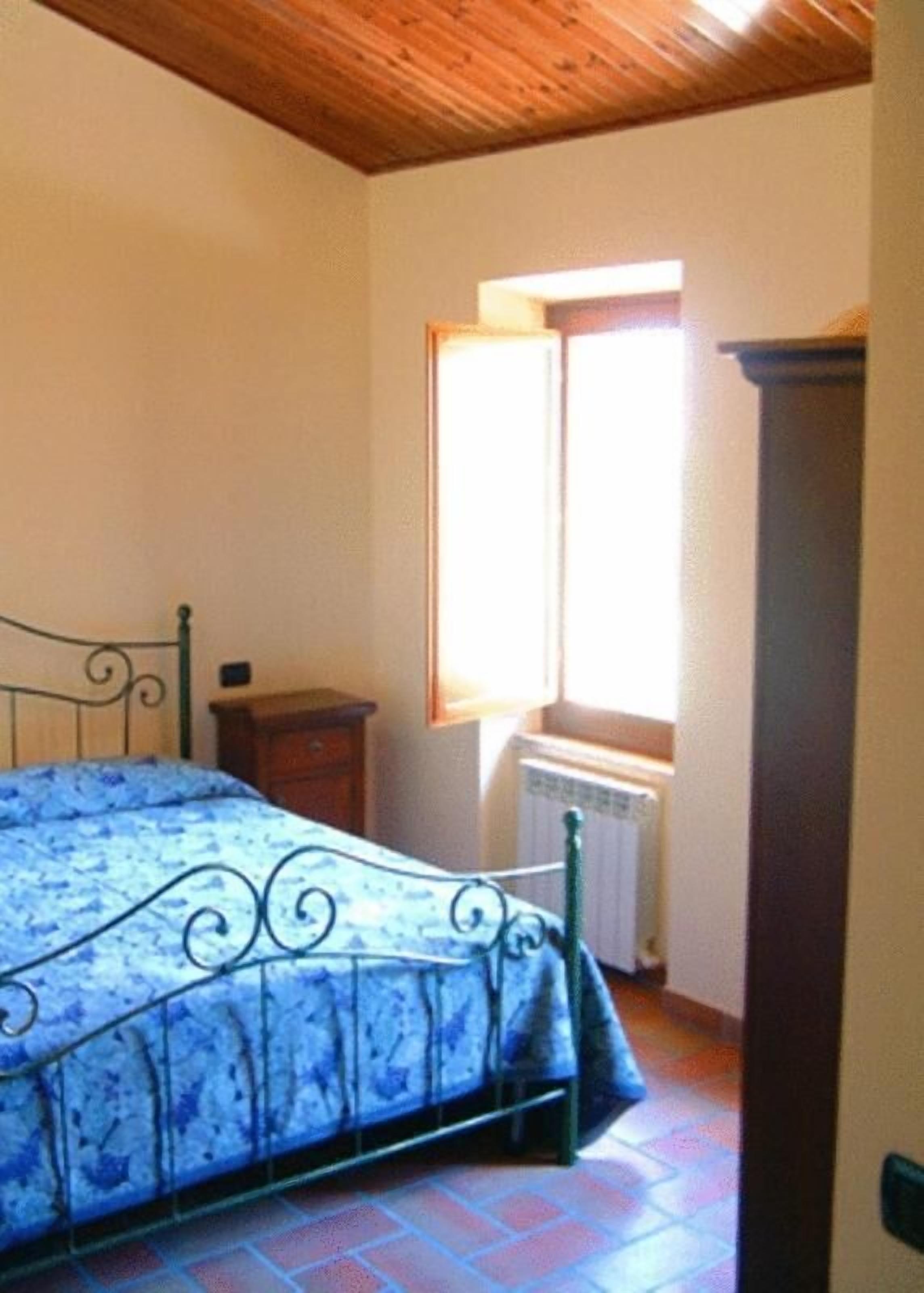 Una camera da letto con un letto, una finestra, un termosifone e un soffitto in legno.