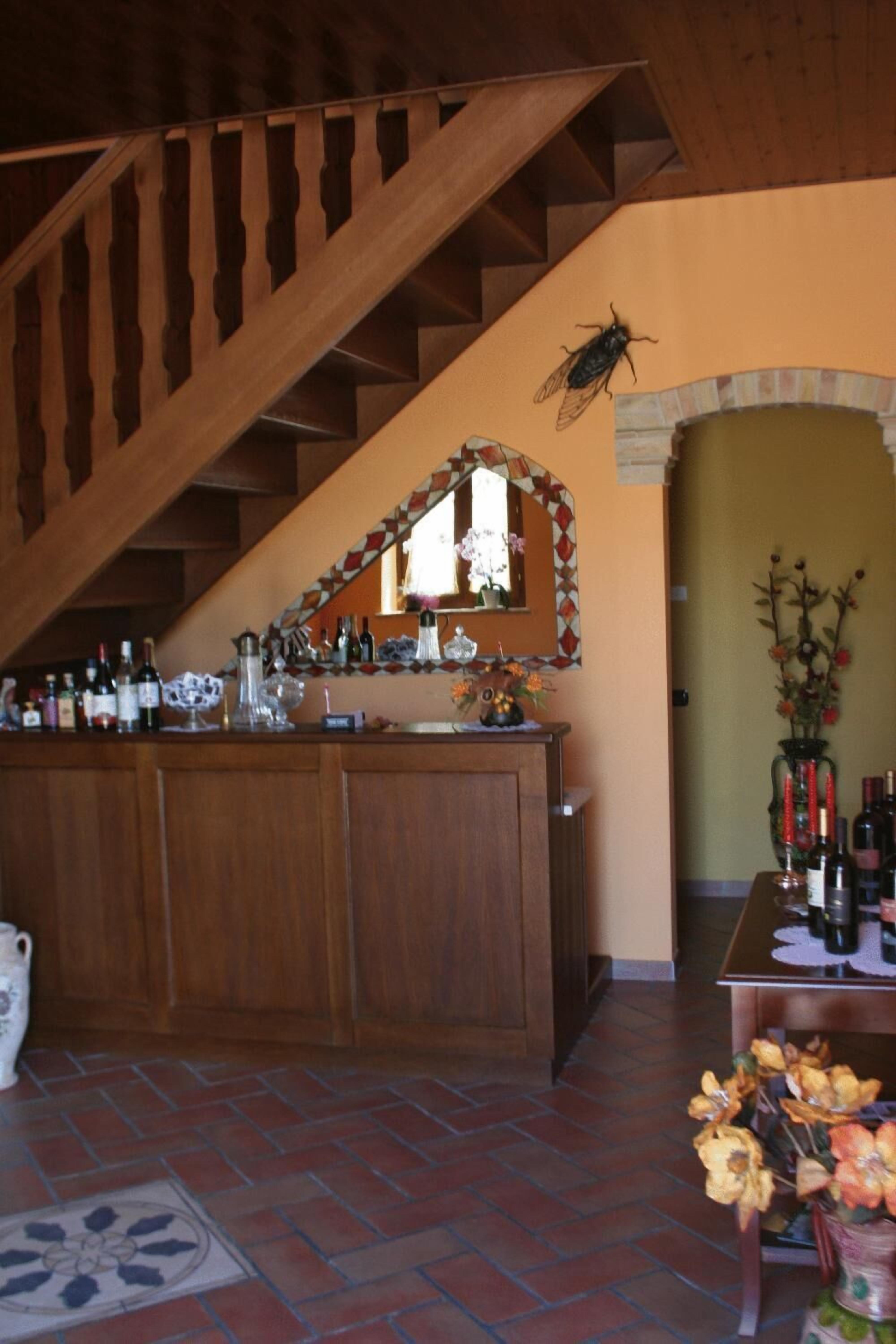 A bar area with wooden cabinets, a mirror, and a staircase.