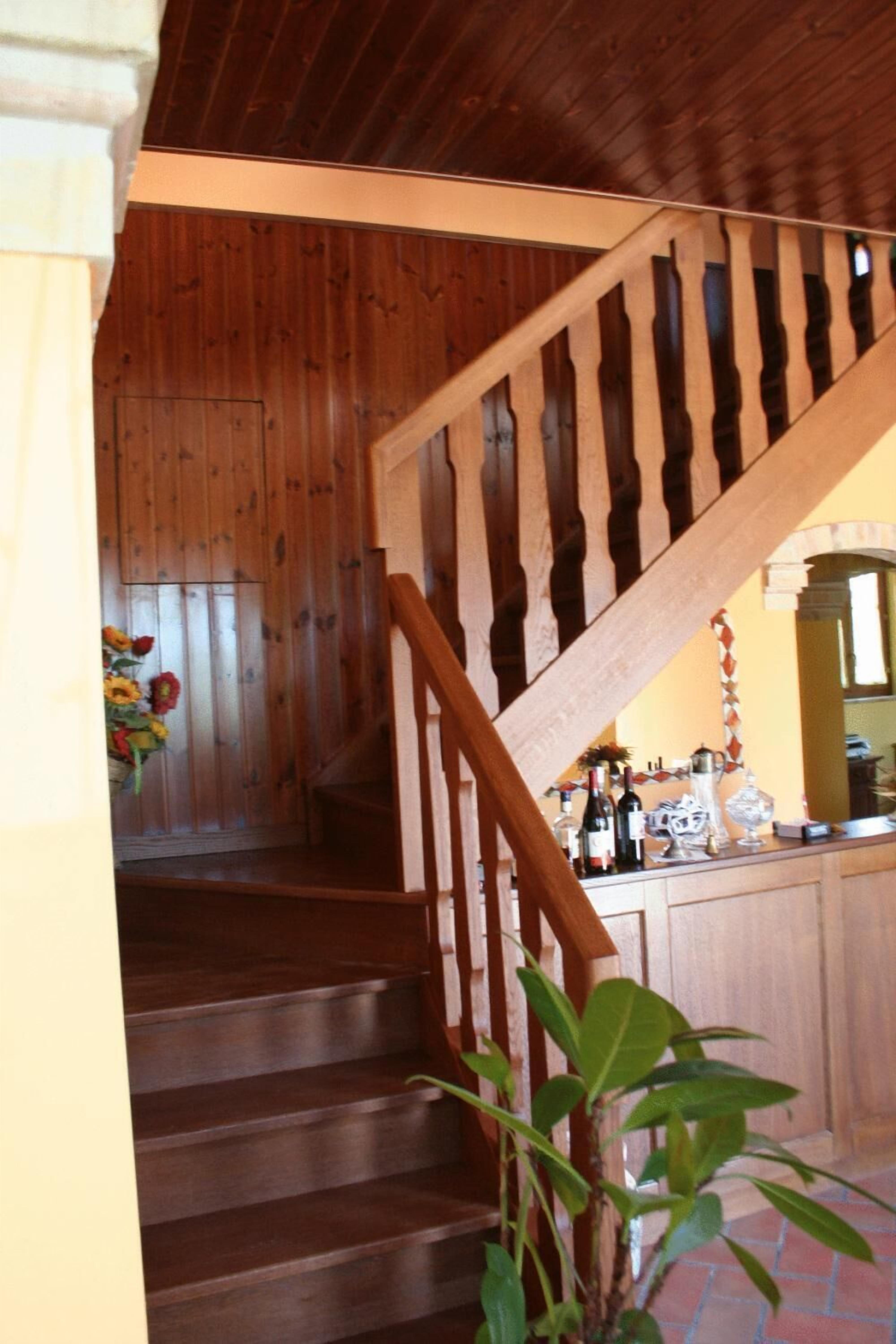 Una escalera de madera que baja a un nivel inferior con una zona de bar al fondo.