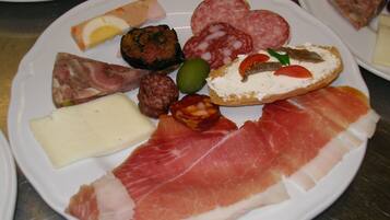 Une assiette garnie de différents types de charcuteries, de fromages et d’olives.