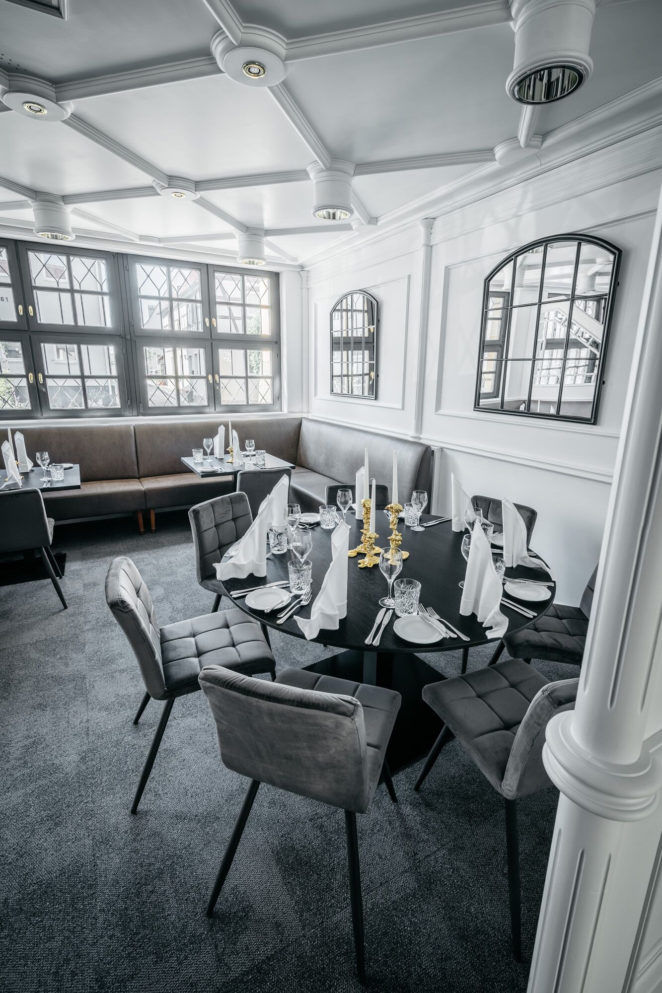 Uma área de jantar com uma mesa redonda posta para quatro pessoas, cercada por cadeiras estofadas.