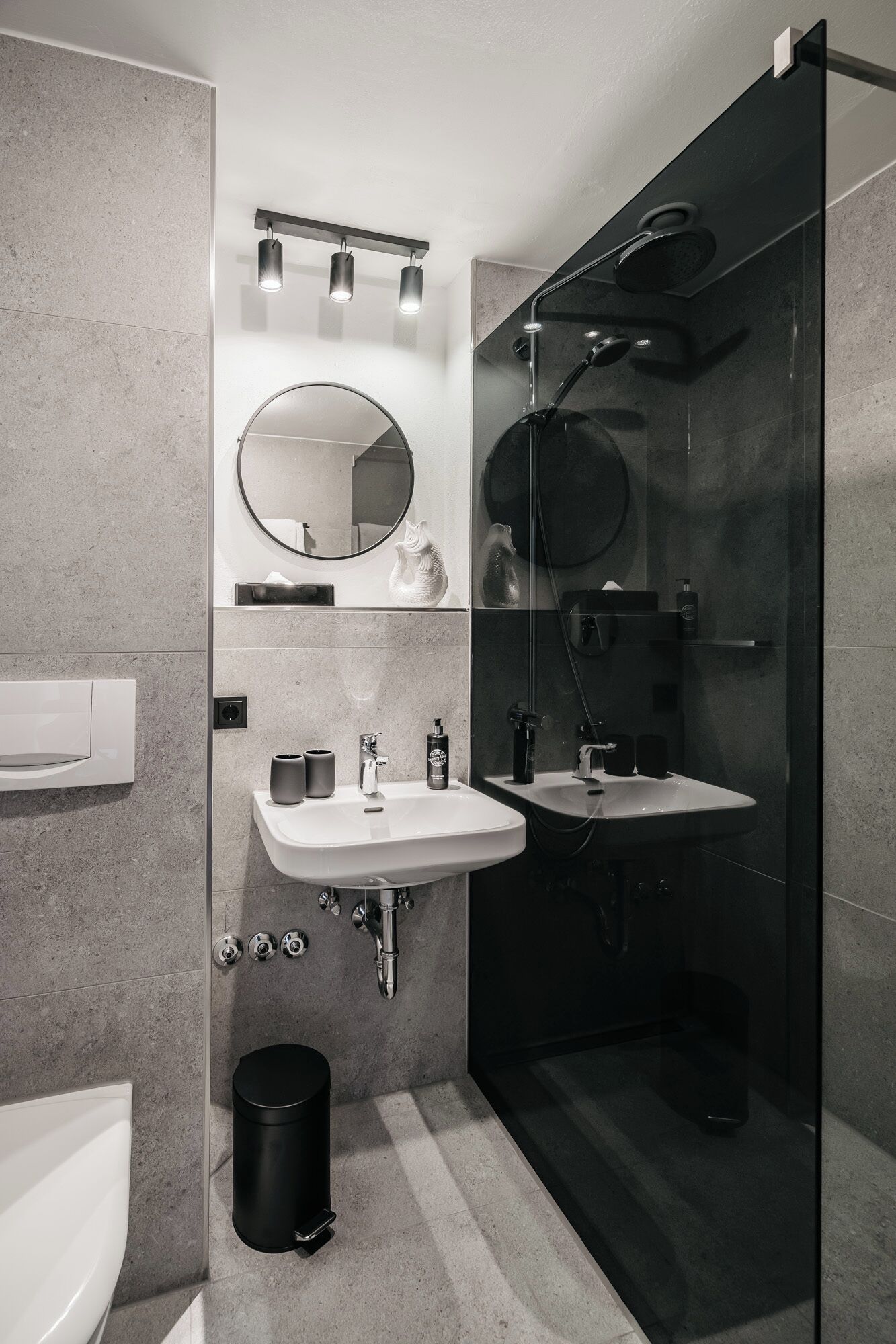 Een moderne badkamer met twee wastafels, een toilet en een douche met glazen wanden.