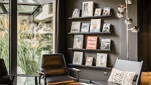Un interior moderno con techo oscuro, una estantería llena de libros y cuadros enmarcados, sillones de cuero y una mesa de centro.