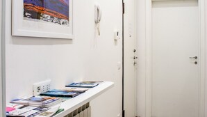 Ein Flur mit einer weißen Tür, einem gerahmten Kunstwerk an der Wand und einer weißen Theke mit Zeitschriften.