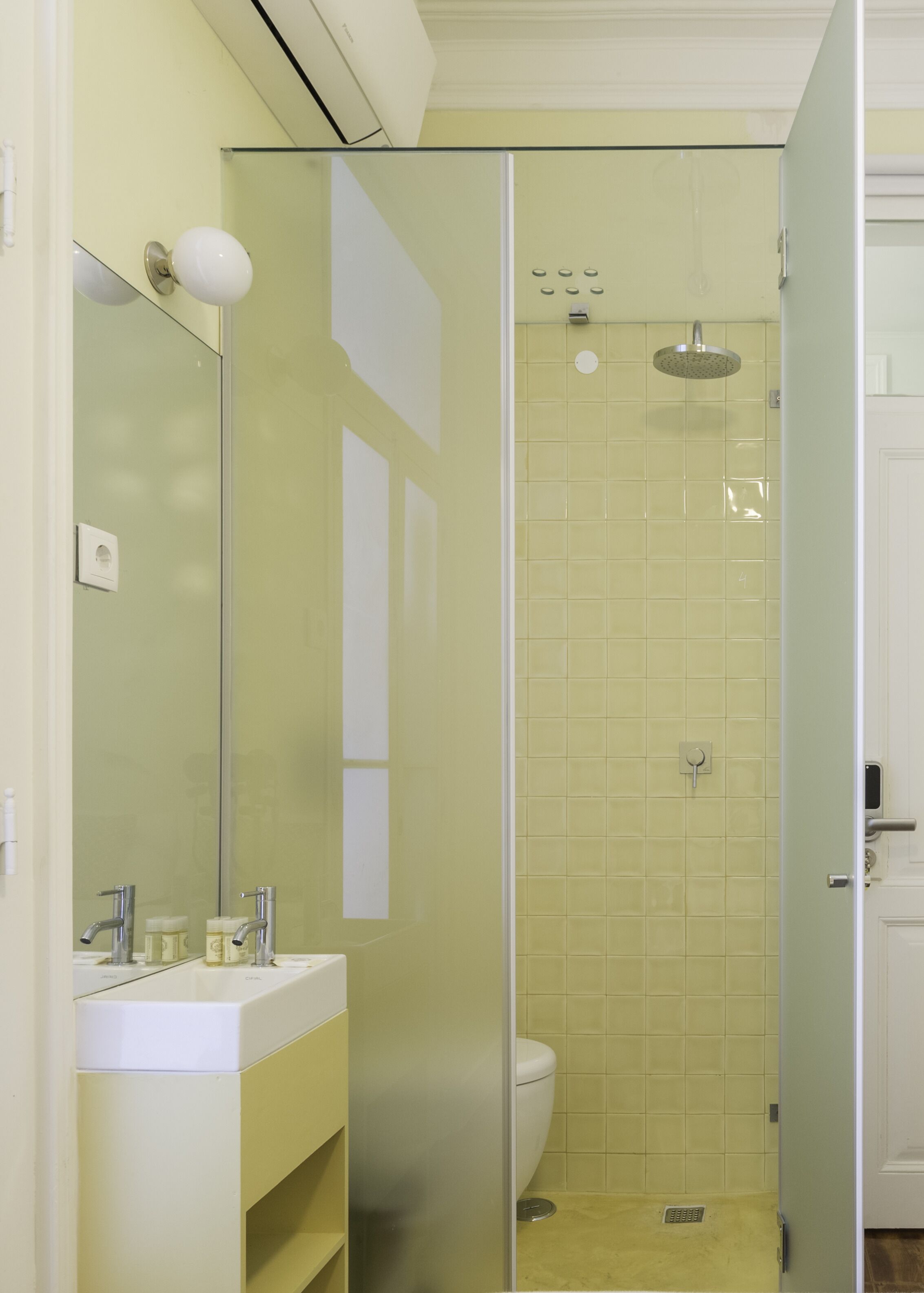 Un baño con cabina de ducha de vidrio, inodoro blanco y tocador con espejo y dos grifos.