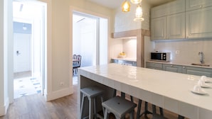 A spacious kitchen with a large island, grey cabinets, and pendant lighting. - 1898 Home & Suites (Lisbon)