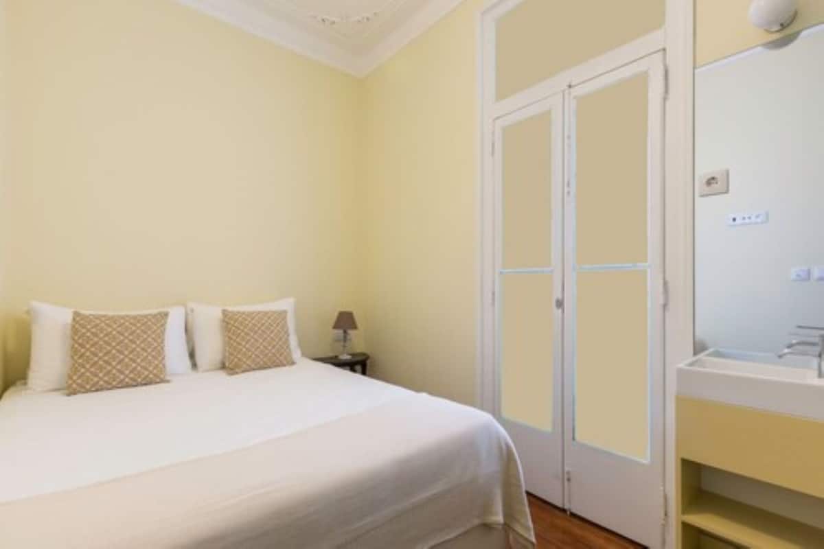 A bedroom with a bed, bedside table, lamp, and a wardrobe with a mirror.