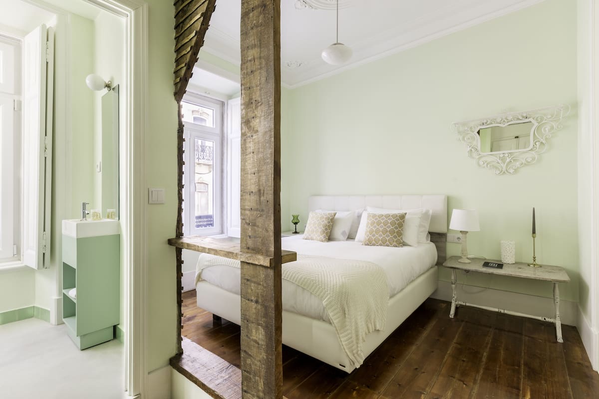 A bedroom with a bed, bedside table, and a mirror on the wall.