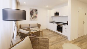 A modern living room with a sofa and a dining table, a kitchen with white cabinets and appliances, and a large window with curtains. - Work Life Residence  (Winterthur)
