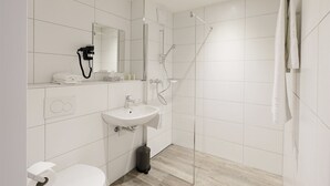 A modern bathroom with white tiles, a sink, a toilet, and a shower. - Work Life Residence  (Winterthur)