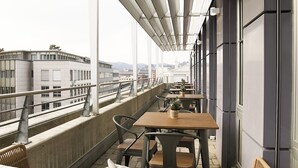 A balcony with tables and chairs, overlooking a cityscape. - Work Life Residence  (Winterthur)