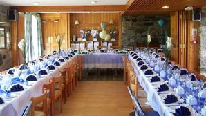 A long dining table set with blue and white tablecloths, wooden chairs, and floral centerpieces. - Gigha Hotel (Isle of Gigha)