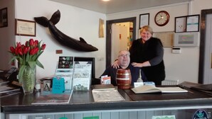 A reception area with a counter displaying various items, a clock, and framed certificates on the wall. - Gigha Hotel (Isle of Gigha)