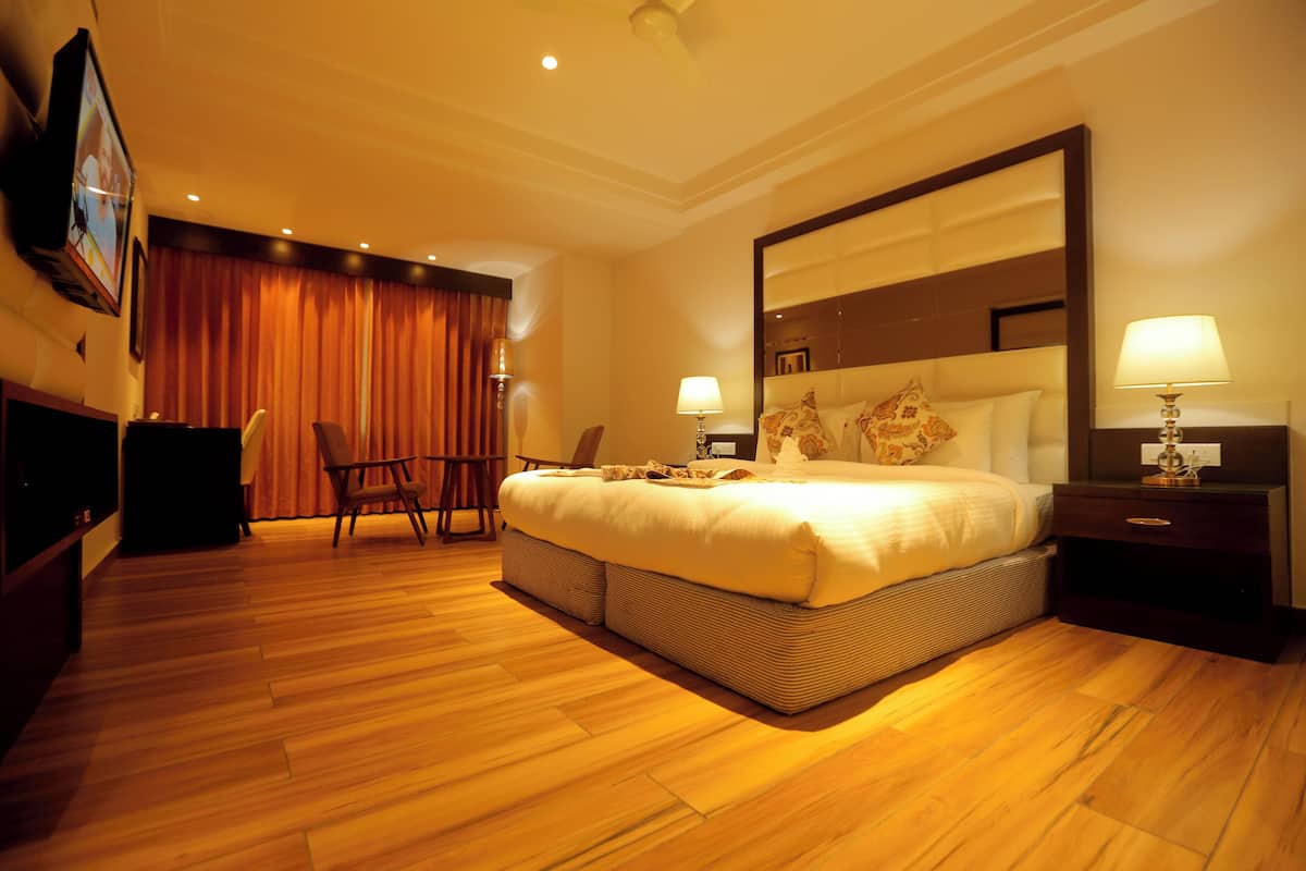 A hotel room with a large bed, a desk, and a chair.