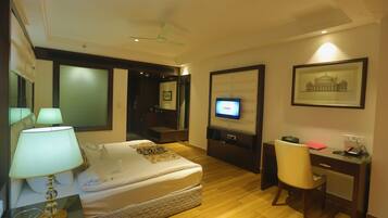 Habitación de hotel con cama, escritorio, silla, televisor y un cuadro en la pared.
