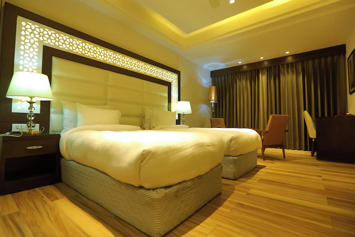 A hotel room with a large bed, two bedside tables, a chair, and a desk.