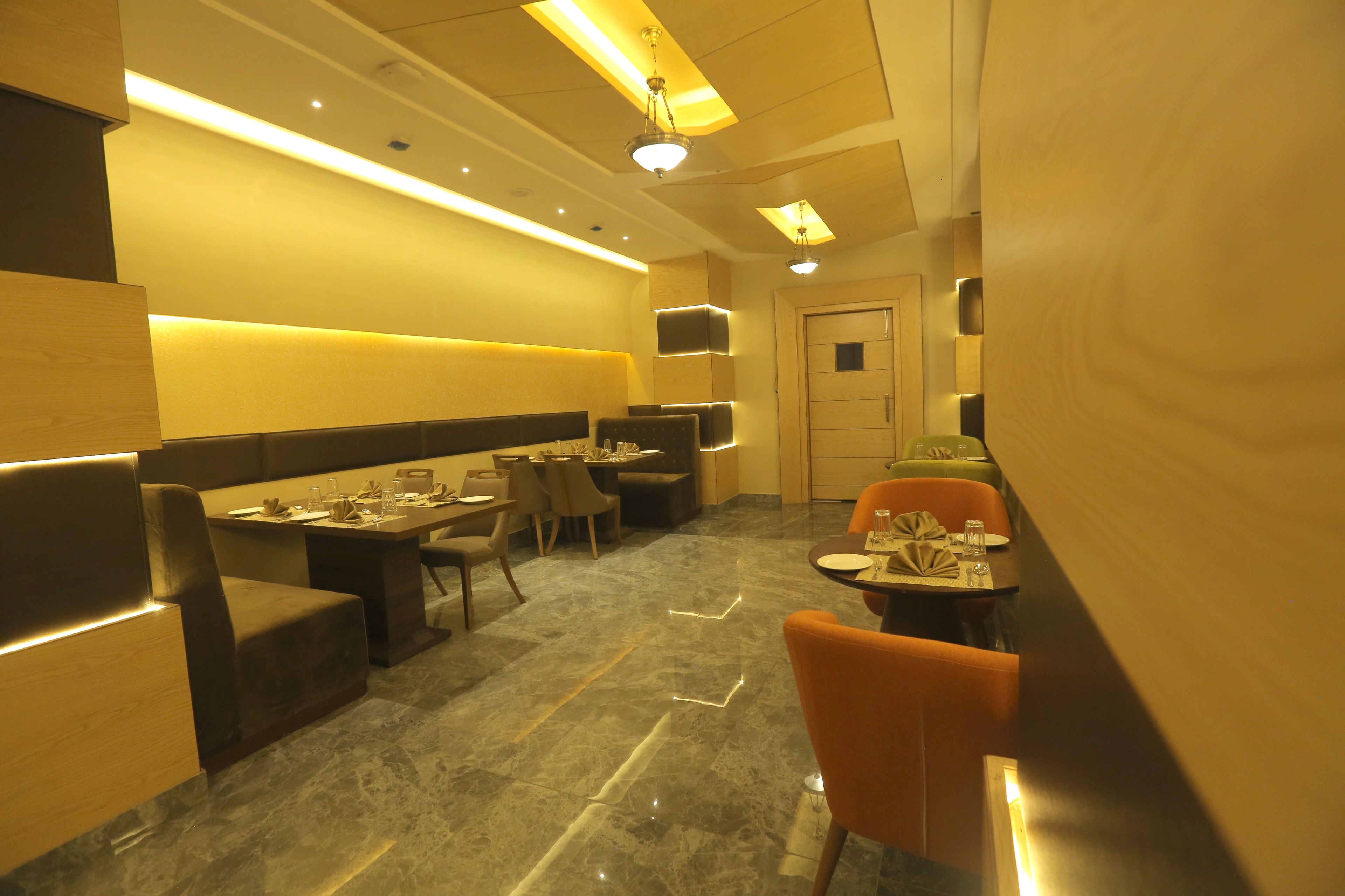 A restaurant with booths and tables, marble flooring, and warm lighting.