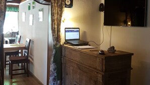 A room with a wooden ceiling, a desk with a laptop, a television mounted on the wall, and a cabinet with a vintage design. - Pension Haus Rohrmoser (Annaberg-Lungoetz)