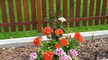 A wooden planter box with flowers on a paved surface.