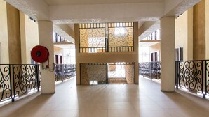 A spacious interior with a high ceiling, tiled floors, and a central open area with a decorative metal gate. - Kings Manor 06 by Pro Homes Jamaica (Kingston)