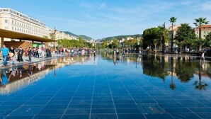 A spacious public square with a reflective floor, surrounded by buildings and palm trees. - Azureva - Roquebrune Cap Martin (Roquebrune-Cap-Martin)