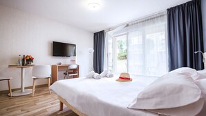 A hotel room with a bed, a desk, a chair, a TV, and a window with curtains. - Azureva - Roquebrune Cap Martin (Roquebrune-Cap-Martin)