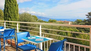 A terrace with blue chairs and tables, overlooking a coastal landscape with trees and a distant view of the sea. - Azureva - Roquebrune Cap Martin (Roquebrune-Cap-Martin)
