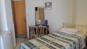 A bedroom with a bed, a desk with a chair, a mirror, and a door. - Delphi Hotel (Nicosia)