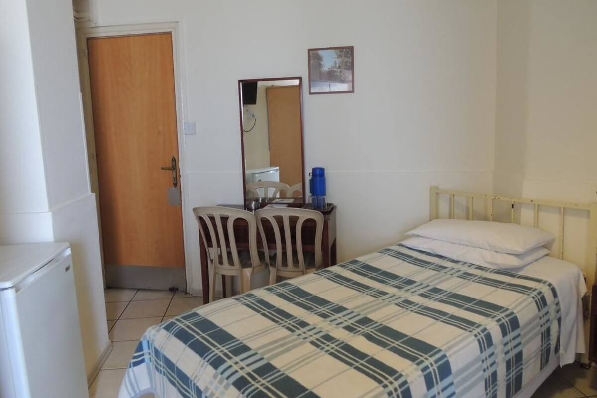 Une chambre à coucher avec un lit, un bureau avec une chaise, un miroir et une porte.