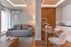 A modern living room with a sofa, coffee table, and dining area with a table and chairs. - P&O Oxygen Wronia 3 (Warsaw)
