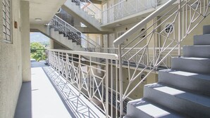 Un edificio de varios niveles con una escalera central, barandillas de metal y vistas a zonas verdes.