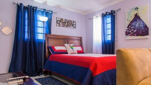 Un dormitorio con cama, cortinas, un cuadro y una silla.