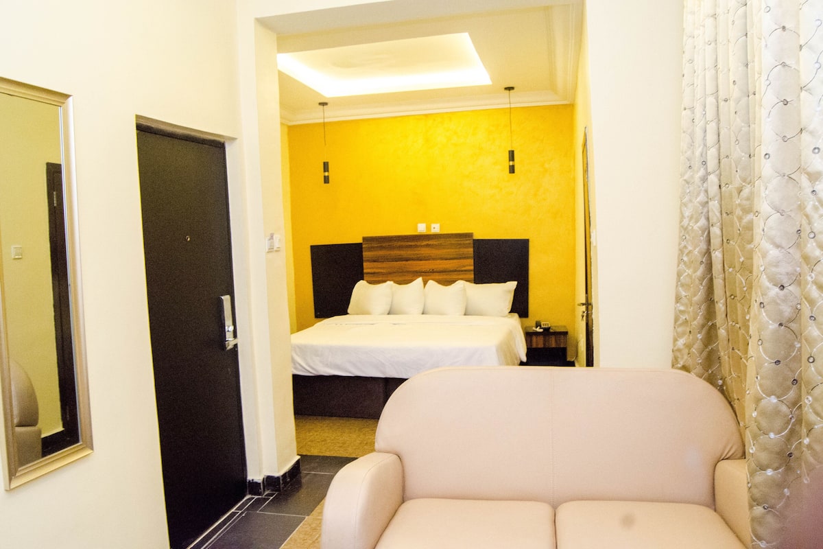 Een hotelkamer met een bed, een stoel, een spiegel en een deur.