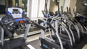 A row of treadmills in a gym with a mirrored wall and a window in the background. - Residency Hotel Guzape Abuja (Abuja)