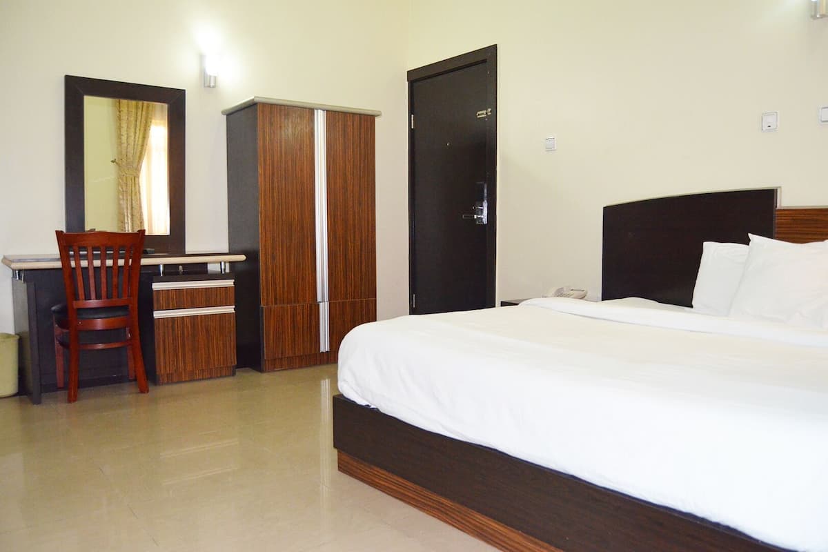 Een hotelkamer met een bed, een bureau, een stoel en een kledingkast.