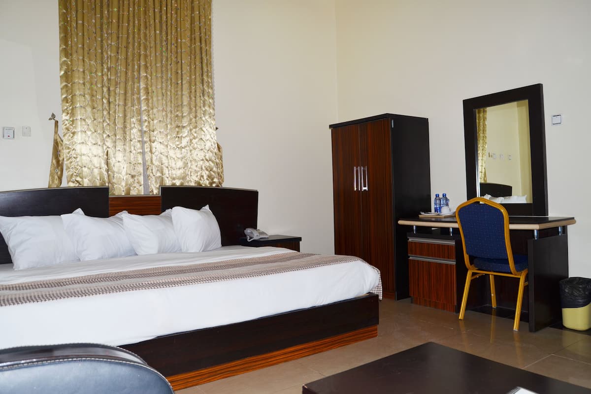 Een hotelkamer met een bed, bureau, stoel en kledingkast.