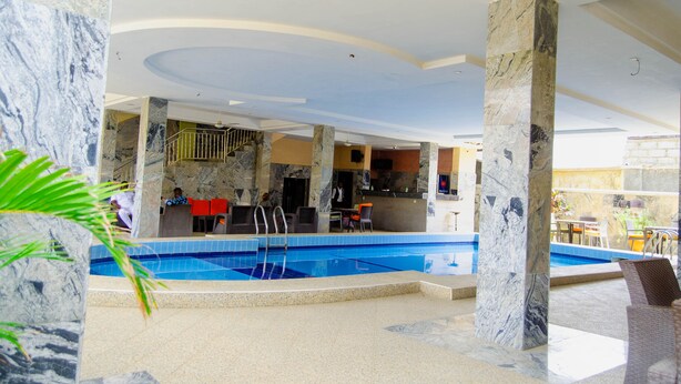 An indoor swimming pool with marble columns, a reception area, and a bar. - Residency Hotel Guzape Abuja (Abuja)