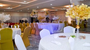A banquet hall with round tables, yellow chairs, white tablecloths, and floral centerpieces. - Residency Hotel Guzape Abuja (Abuja)