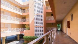 A multi-level building with balconies, a covered walkway, and a parking area. - Strathairn 110 by Pro Homes Jamaica (Kingston)