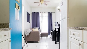 A compact living space with a kitchenette, a ceiling fan, a sofa, and a dining table. - Strathairn 110 by Pro Homes Jamaica (Kingston)
