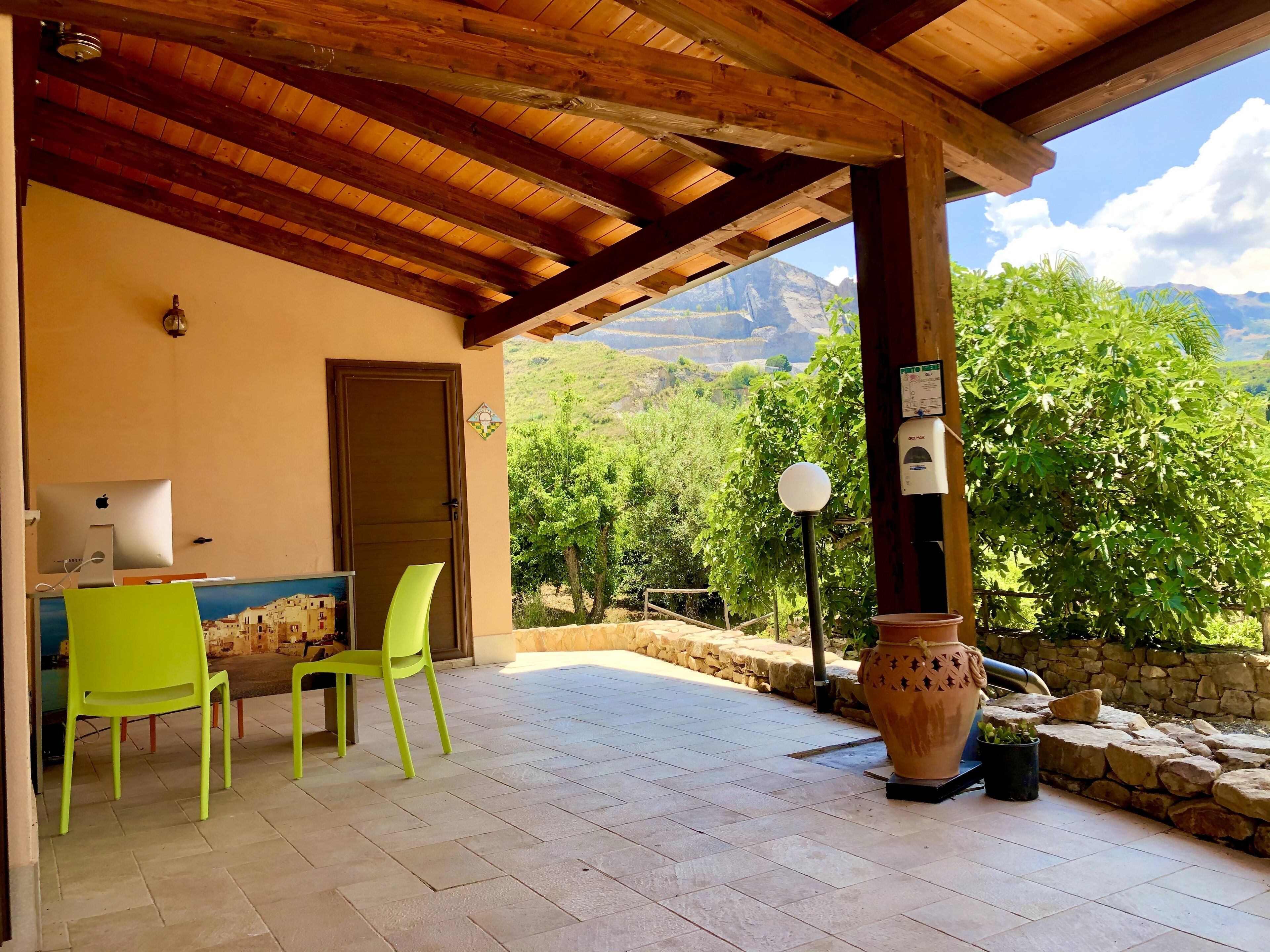 A room with a wooden ceiling, a door, a desk with a computer, two chairs, and a view of mountains.