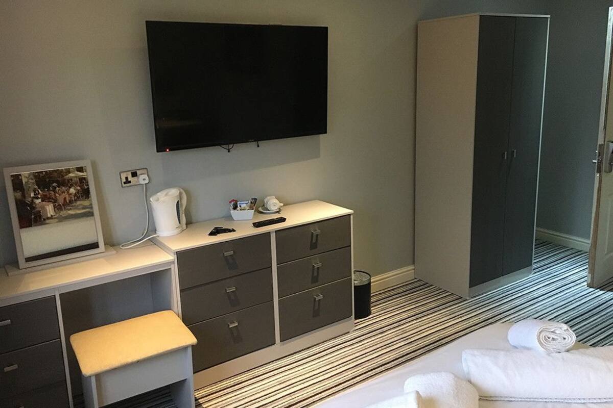 Une chambre d’hôtel comprenant un lit, un bureau avec un téléviseur à écran plat, une armoire et un tableau encadré au mur.