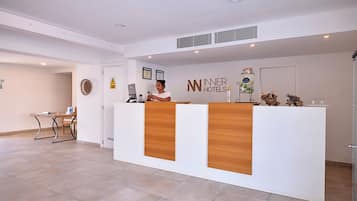 A reception desk with a logo, a computer, and a small table with chairs.