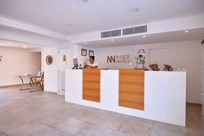 A reception desk with a logo, a computer, and a small table with chairs. - INNER Hotel Rupit - Adults Only (Santanyi)