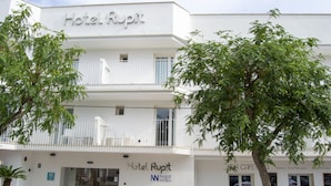 A hotel named Hotel Rupit with a white facade, a balcony with white railings, and outdoor seating area. - INNER Hotel Rupit - Adults Only (Santanyi)