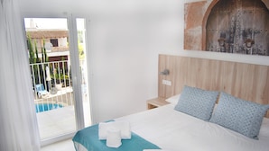 A hotel room with a bed, a view of a pool, and a wooden door. - INNER Hotel Rupit - Adults Only (Santanyi)