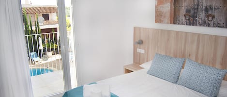 Una camera d'albergo con un letto, vista su una piscina e una porta in legno.